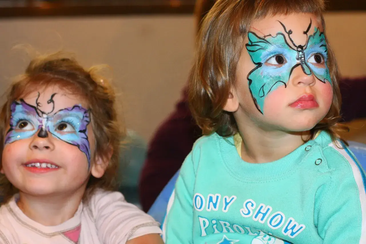 Bambine con colorate maschere di carnevale facili a forma di farfalla dipinte sul viso, pronte per la festa.