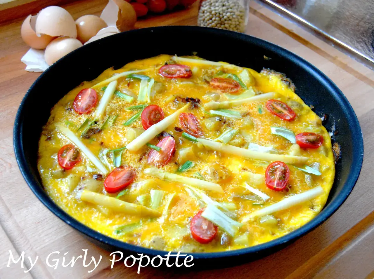 Omelette aux asperges vertes et oignons, garnie de tomates cerises, prête à être dégustée. Une recette simple et savoureuse.