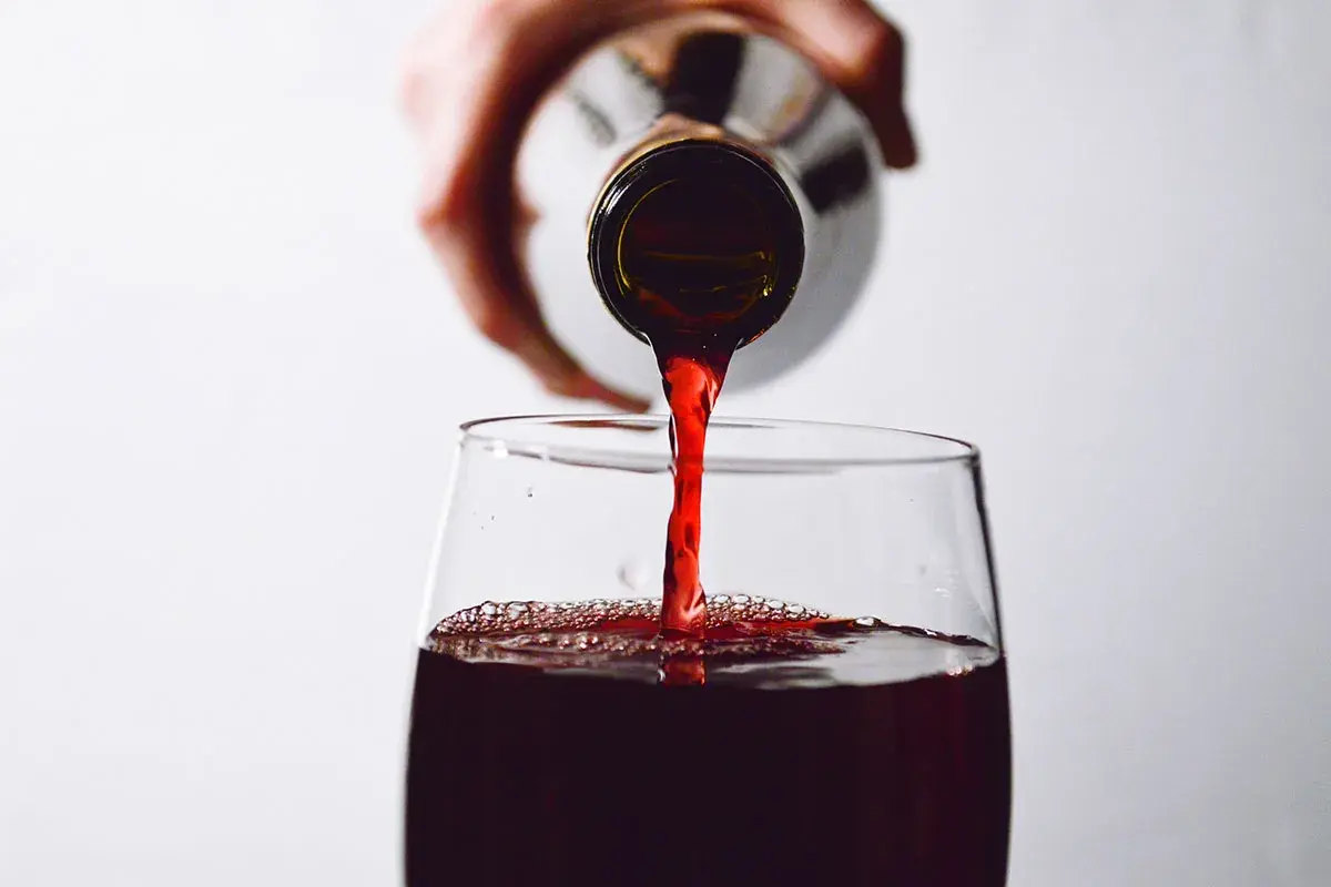 Rotwein wird in ein Glas gegossen. Die Frage, ob man Rotwein nach 2 Wochen noch trinken kann, beschäftigt viele Genießer.