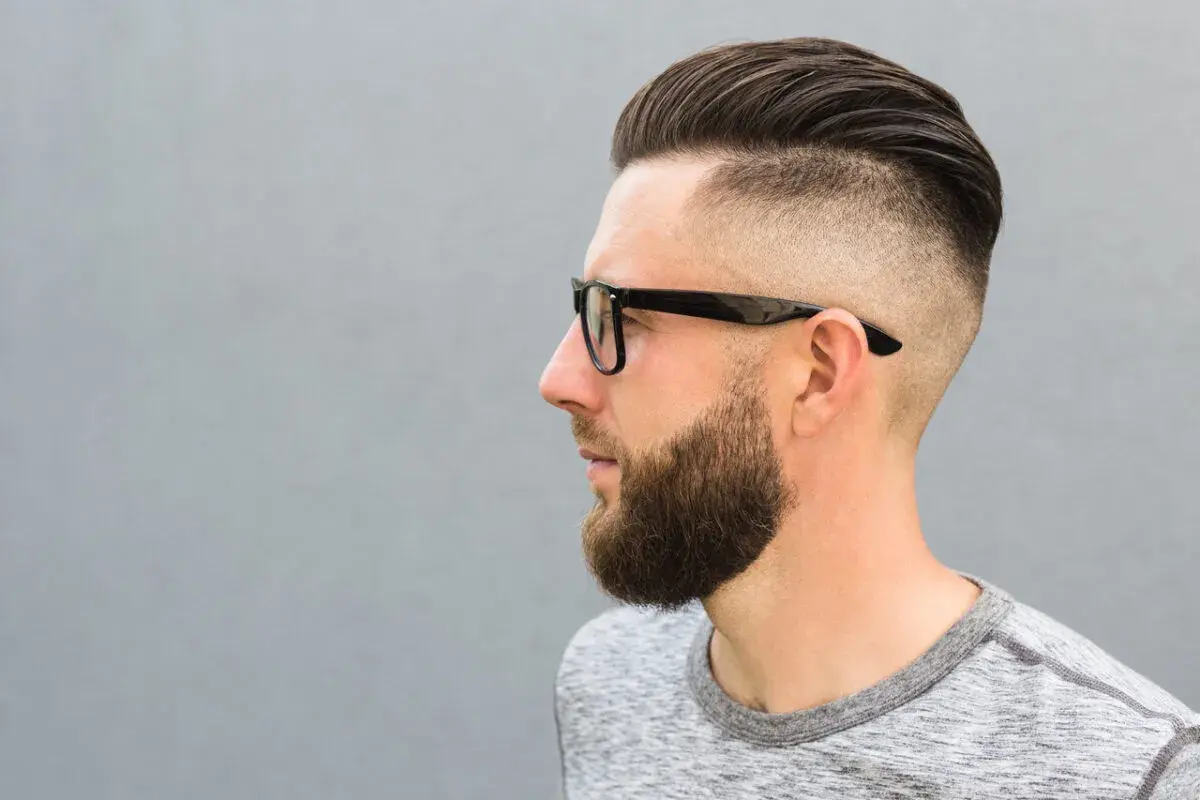 Mężczyzna z zarostem i modnym buzz cut, który sprytnie maskuje zakola.
