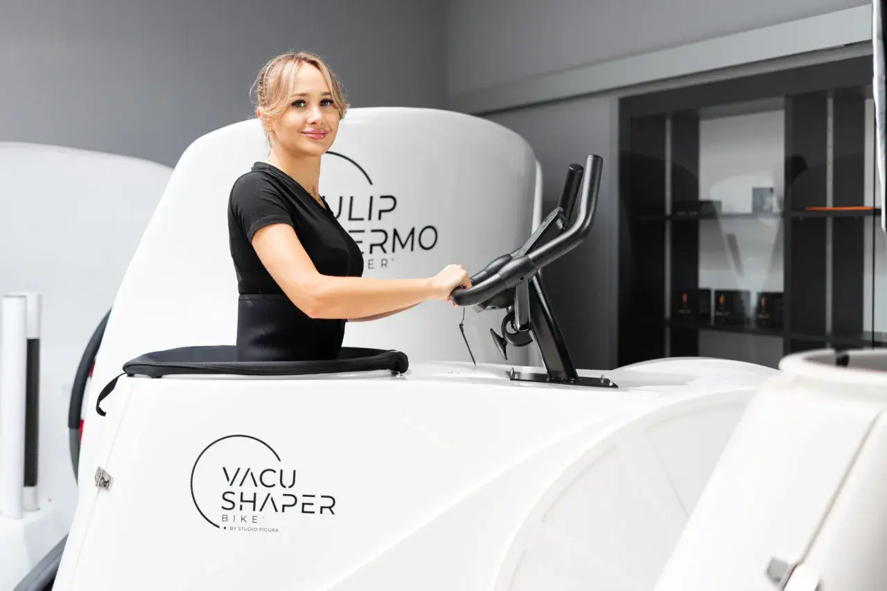 Kobieta ćwiczy na rowerze Vacu Shaper, by osiągnąć wymarzone efekty.