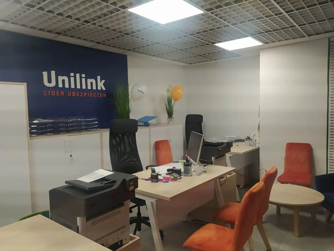Nowoczesne biuro z logo Unilink, meblami i sprzętem biurowym.