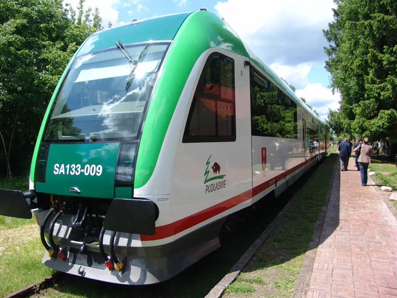 Nowy szynobus Białystok Suwałki czeka na pasażerów. Zielono-biały pojazd z logo Podlasia gotowy do podróży.
