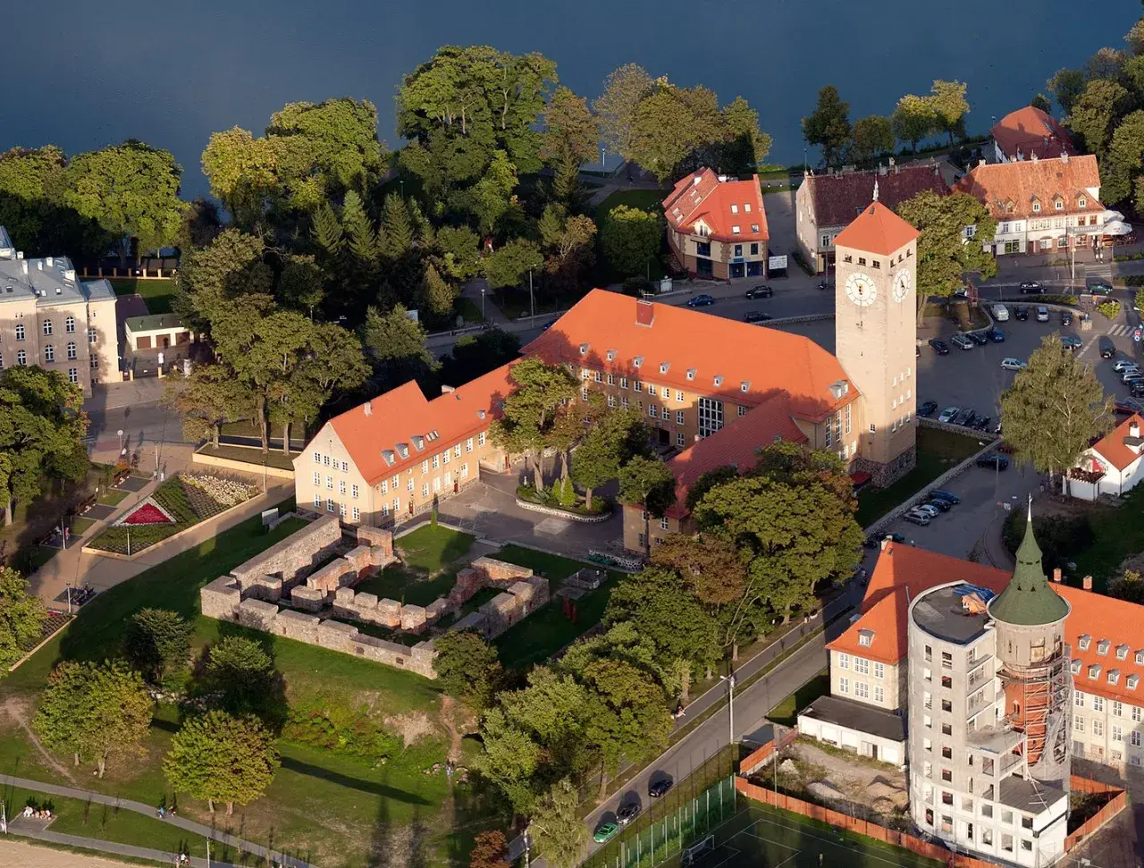 Szczytna atrakcje: ruiny zamku, wieża zegarowa i budynki nad jeziorem.