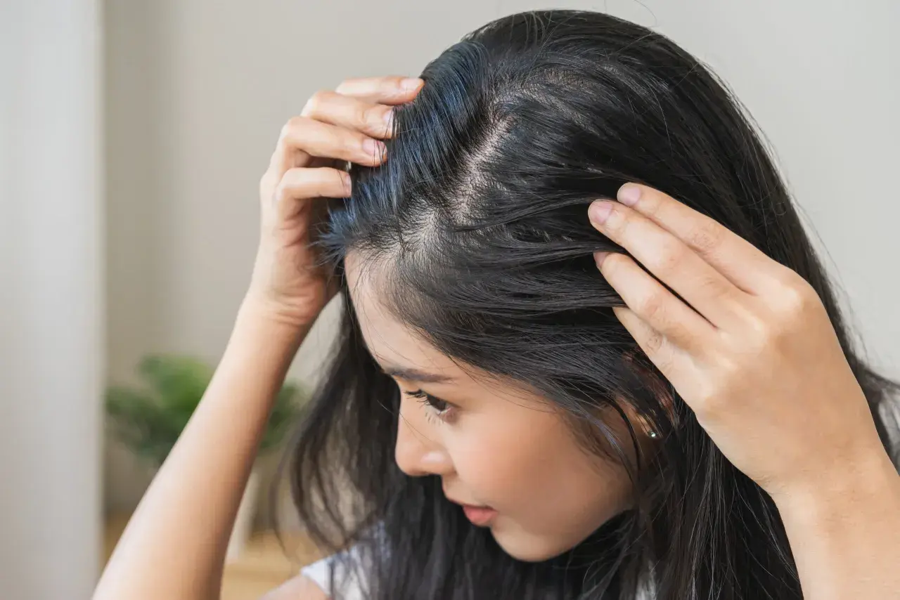 Kobieta sprawdza swoje włosy, zastanawiając się, jak pozbyć się baby hair.