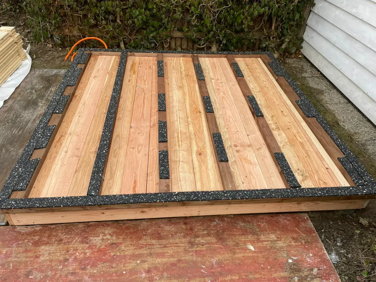 Holzboden für Gartenhaus mit schwarzer Feuchtigkeitssperre am Boden.