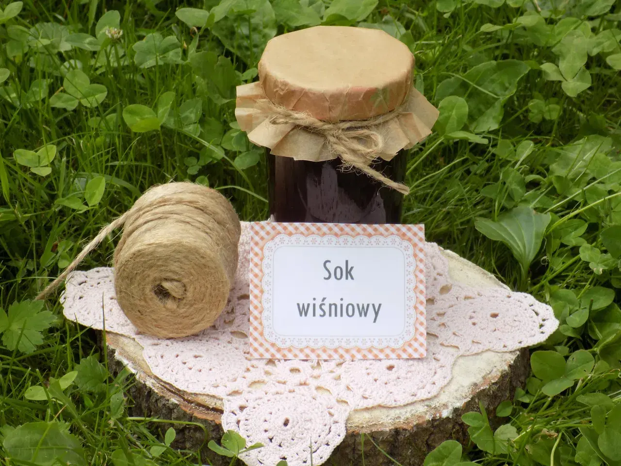 Sok z wiśni przepis: słoik domowego soku, sznurek i serwetka na pniu drewna. Idealny na lato!