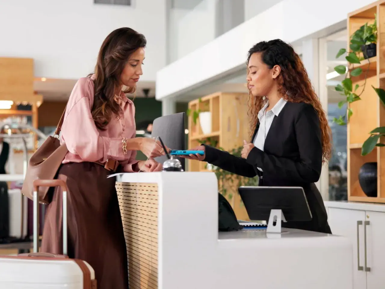 Donna effettua il check-in in hotel, mostrando il suo documento alla receptionist. L'orario del check-in è rispettato.