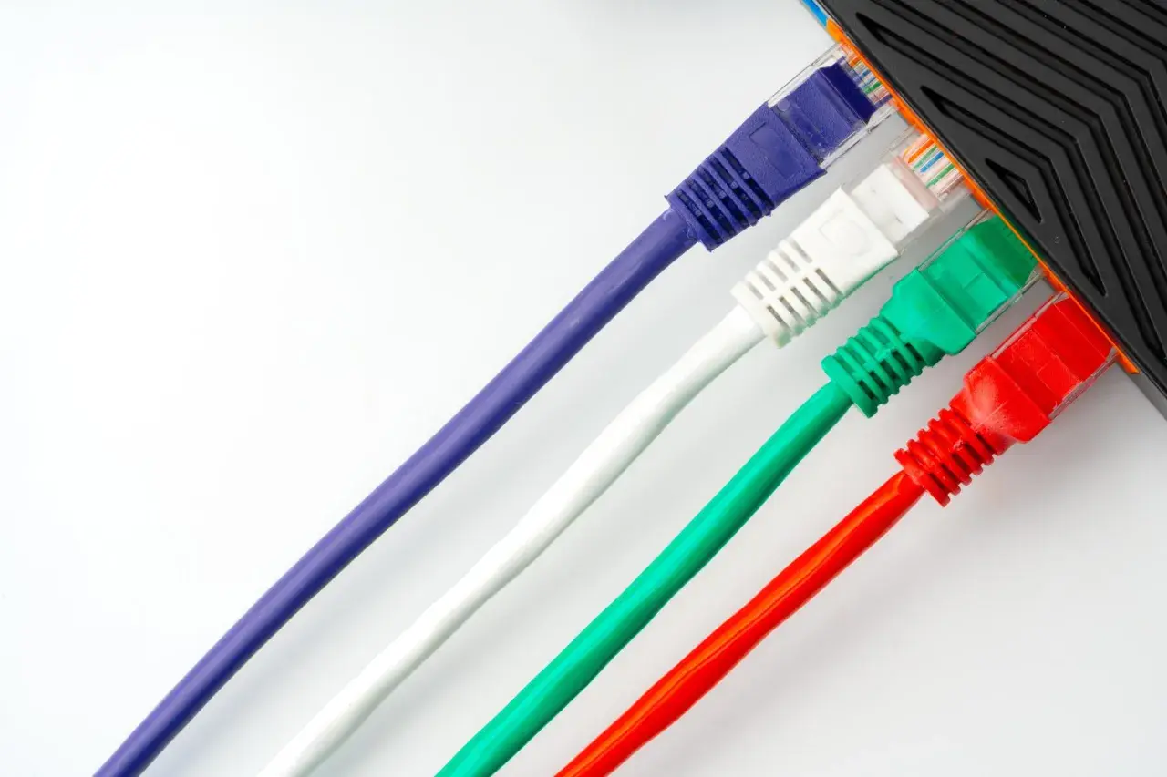 Cables de red de colores (morado, blanco, verde, rojo) conectados a un dispositivo.