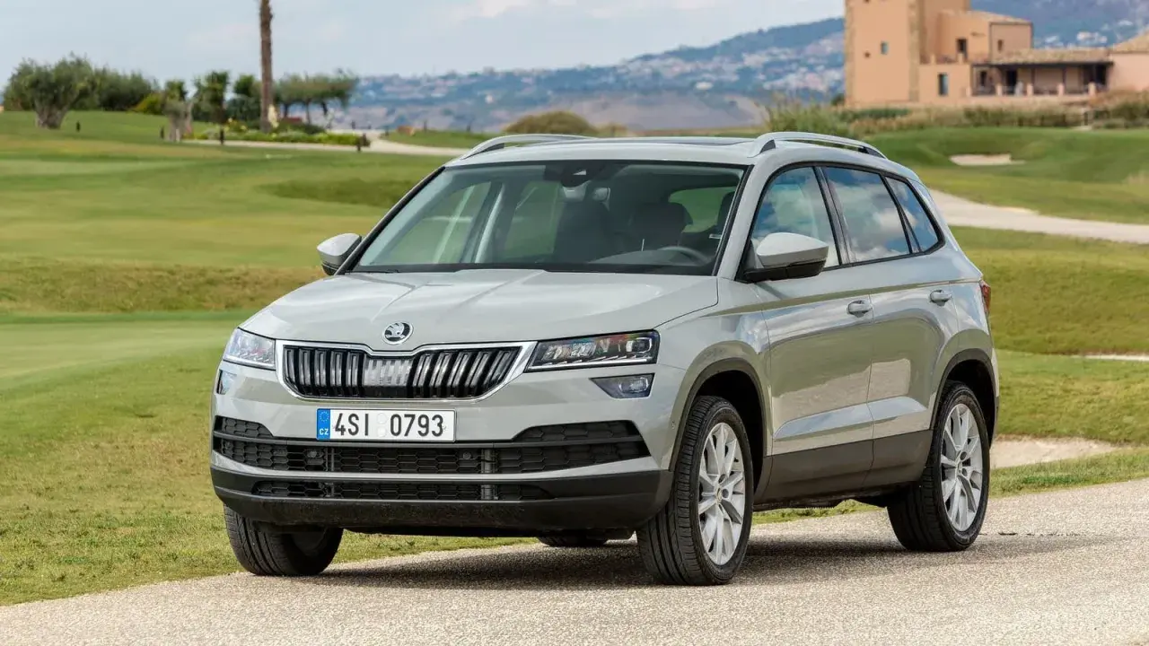 Szary Skoda Karoq na tle zielonych wzgórz. Wiele osób szuka skoda karoq opinie przed zakupem.