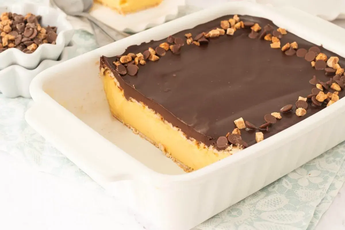 Tarta de natillas y galletas con cobertura de chocolate y trocitos de galleta y chocolate.