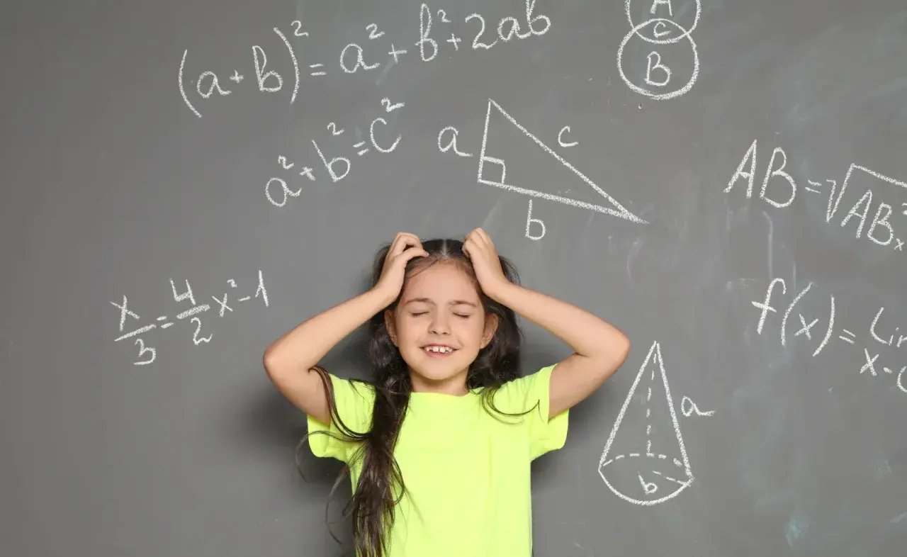 Dziewczynka z rękami wplątanymi we włosy, wyraźnie przeżywająca problemy z matematyką. Wokół niej wzory i figury geometryczne na tablicy.