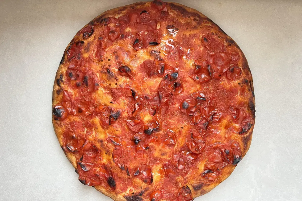 Focaccia rossa con pomodorini succosi e crosta dorata, un'esplosione di sapore mediterraneo.