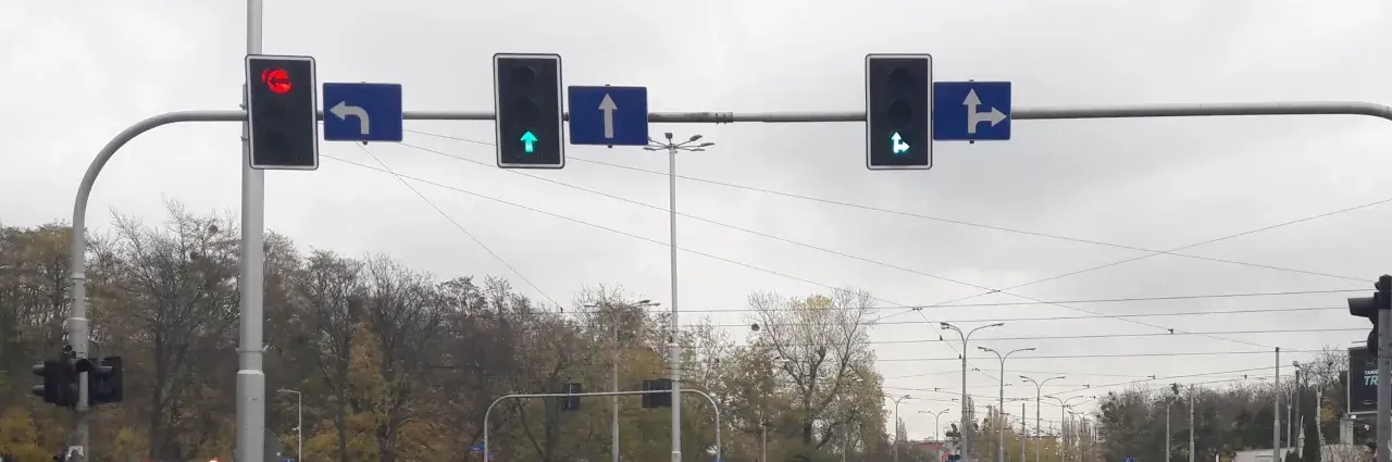 Sygnalizacja świetlna z zieloną strzałką do przodu i w prawo, zieloną strzałką do przodu, czerwoną strzałką w lewo. Znak S3 informuje o dozwolonych kierunkach jazdy.