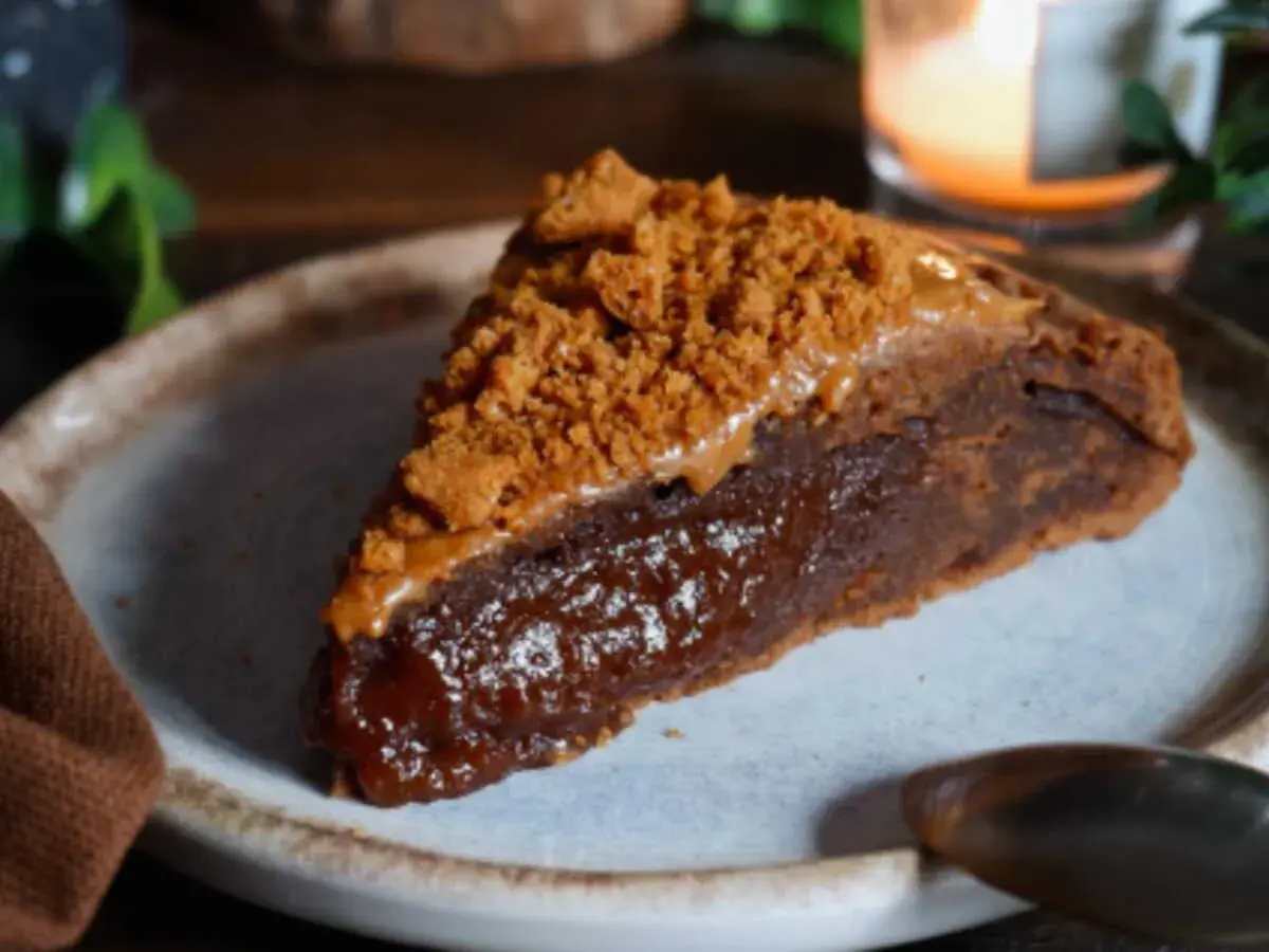 Une part de gâteau speculoos, riche et gourmande, garnie de miettes de biscuits et d'une sauce caramel.