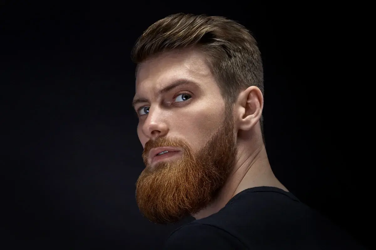 Hombre con barba y peinado moderno, ejemplo de cortes de pelo hombre elegante.