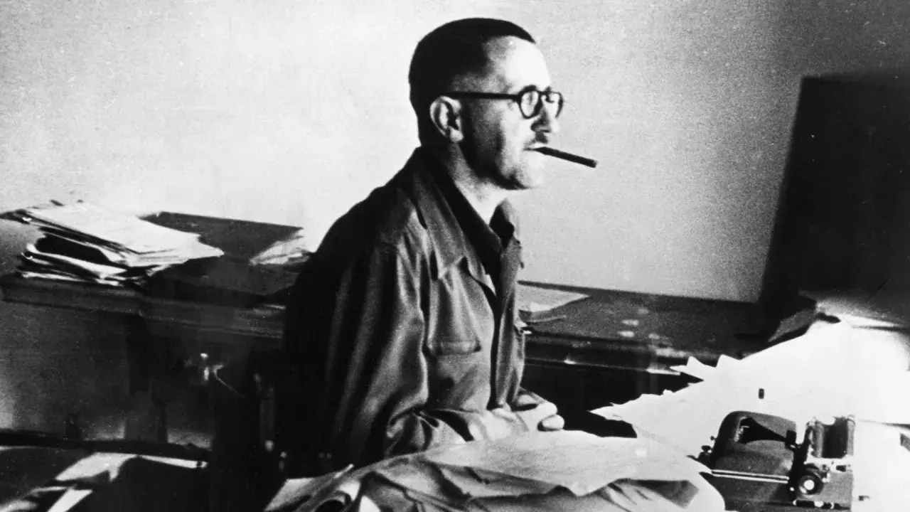 Bertolt Brecht, mit Brille und Zigarre, am Schreibtisch. Er starb 1956.