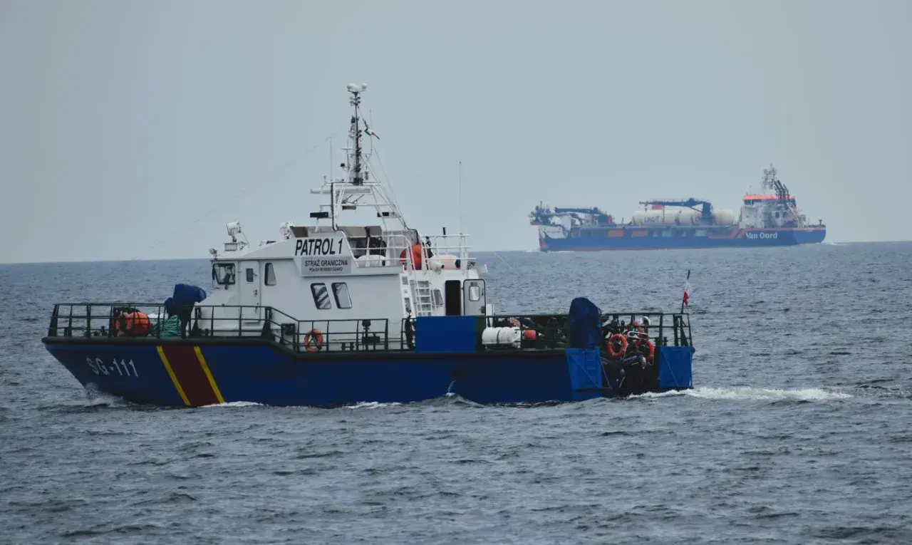 Kuter Straży Granicznej "PATROL 1" płynie po morzu. W tle widać duży statek "Van Oord".