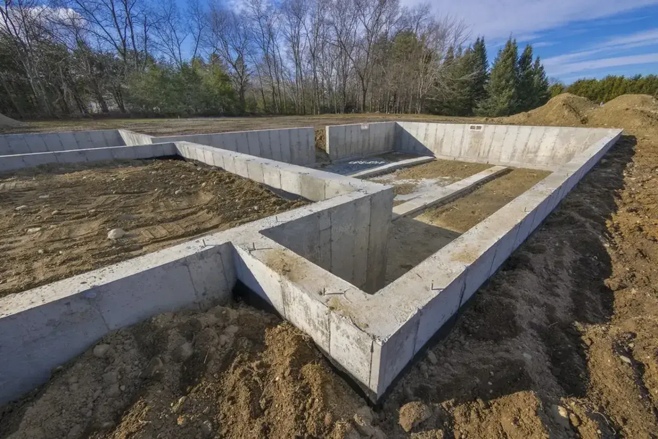 Fundament domu w budowie, z widocznymi różnymi rodzajami betonu, tworzy solidną podstawę dla przyszłego budynku.