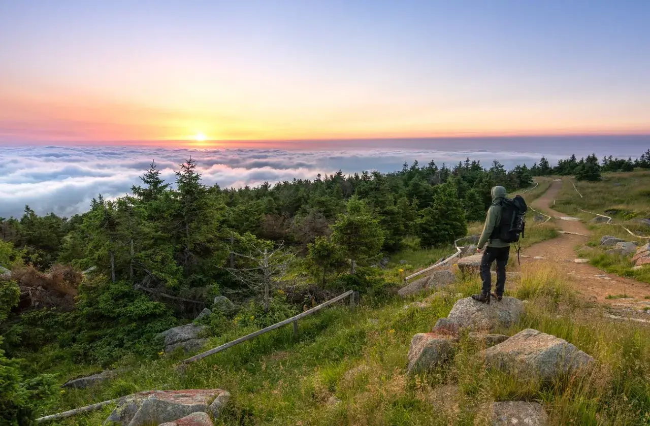 Wanderer genießt Sonnenaufgang über Wolkenmeer. Auf dem Brocken kann man wandern, die Natur bestaunen und den Ausblick genießen.