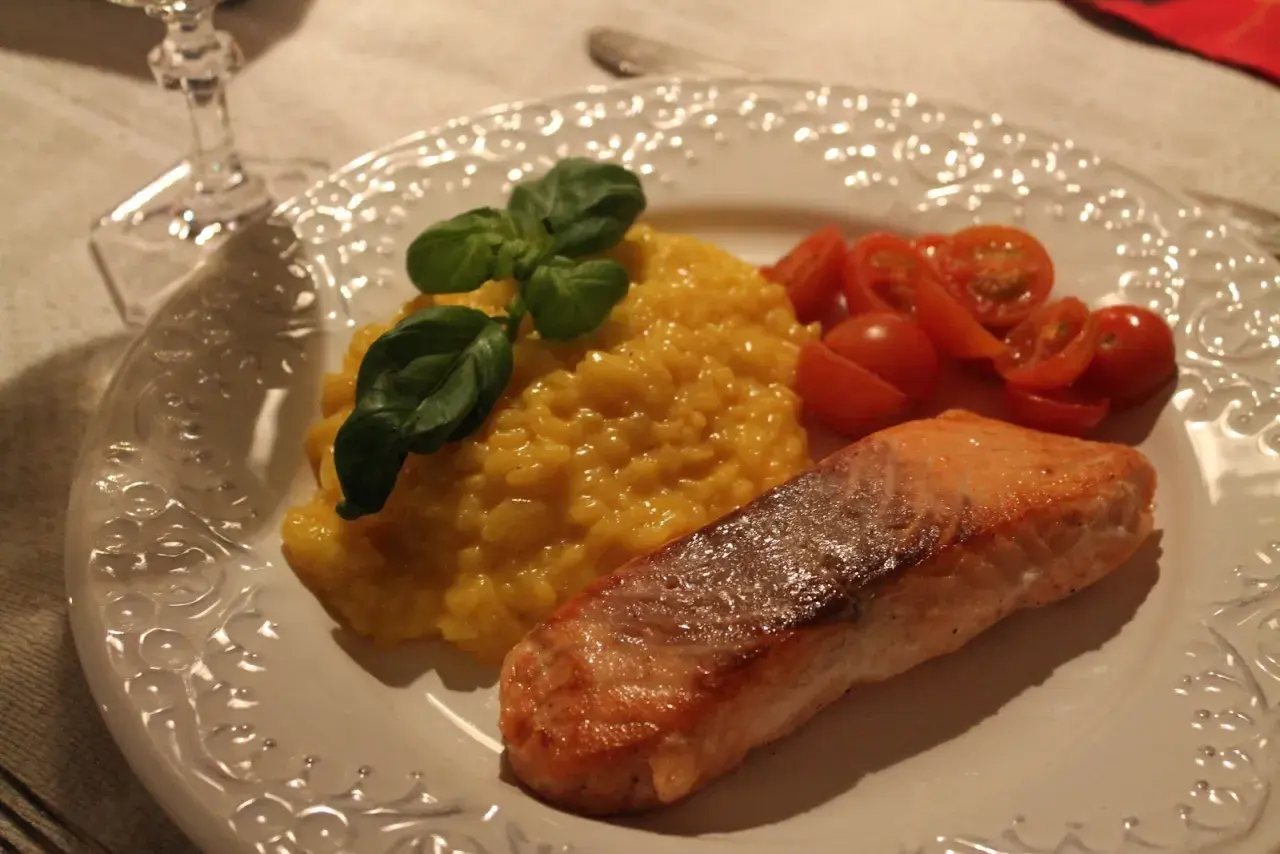 En härlig saffransrisotto med lax, garnerad med basilika och serverad med körsbärstomater. En festlig rätt!