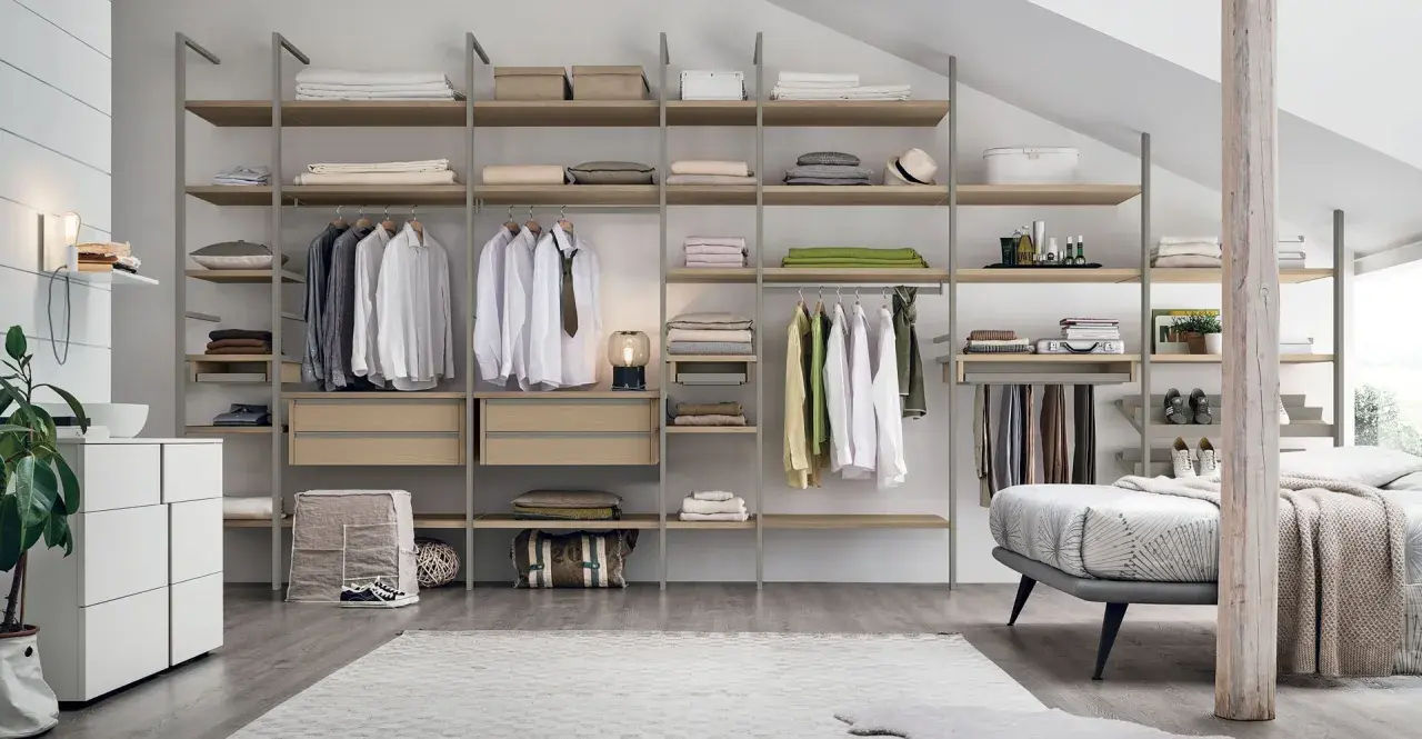 Una cabina armadio mansarda bassa, con scaffali in legno e metallo, ospita abiti ordinati e accessori.