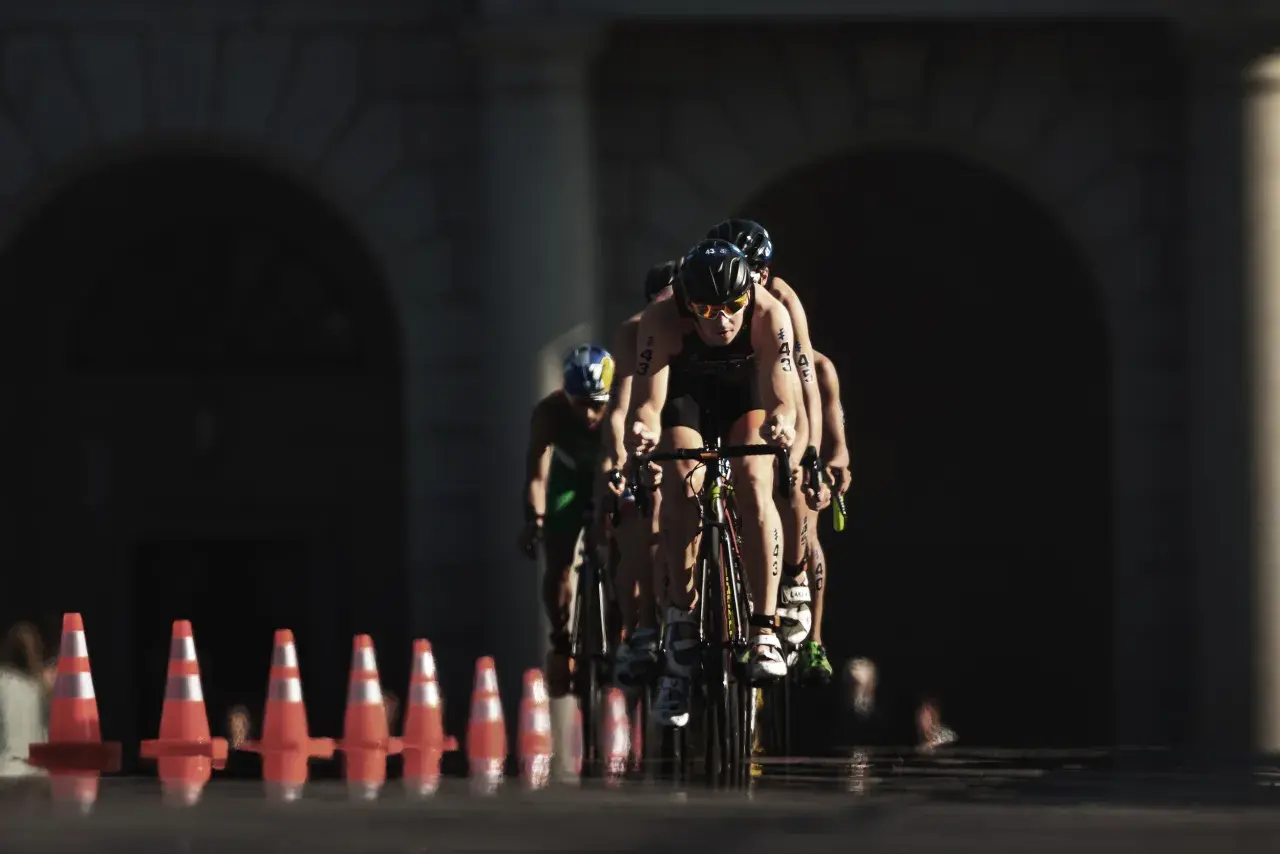 Athletes compete in an Olympic triathlon cycling race, focused and determined as they push forward.