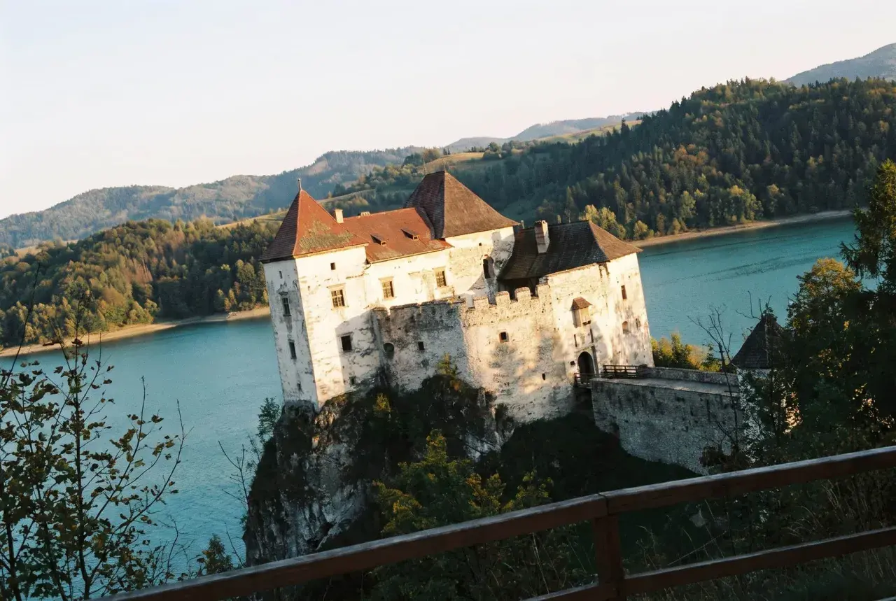 Niedzica-zamek trasa: malowniczy zamek na skale nad turkusową wodą, otoczony zielonymi wzgórzami.