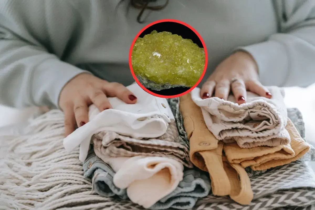 Manos doblando ropa limpia, con una piedra amarilla brillante que evoca el olor a mercaptano.