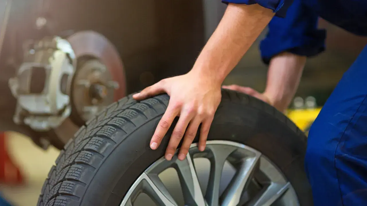 Mecánico revisa un neumático, pensando cuánto duran las ruedas de un coche.