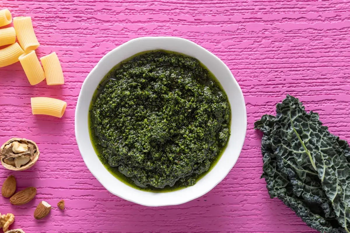 Pesto di cavolo nero crudo, ricco e vibrante, pronto per condire la pasta. Noci e mandorle completano gli ingredienti.