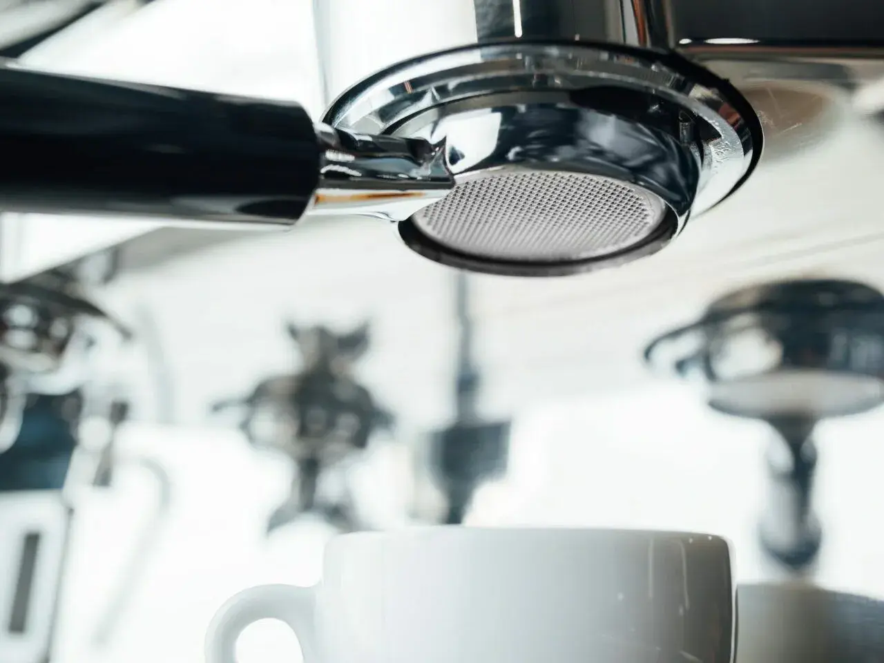 Filtr ekspresu DeLonghi, biała filiżanka i inne elementy. Zbyt częste odkamienianie ekspresu Delonghi może prowadzić do jego uszkodzenia.