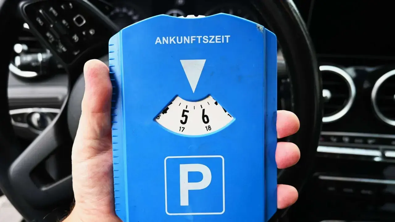 Blaue Parkscheibe mit "Ankunftszeit" und "P"-Symbol. Beachten Sie die Parkuhr Regeln für die korrekte Einstellung der Ankunftszeit.