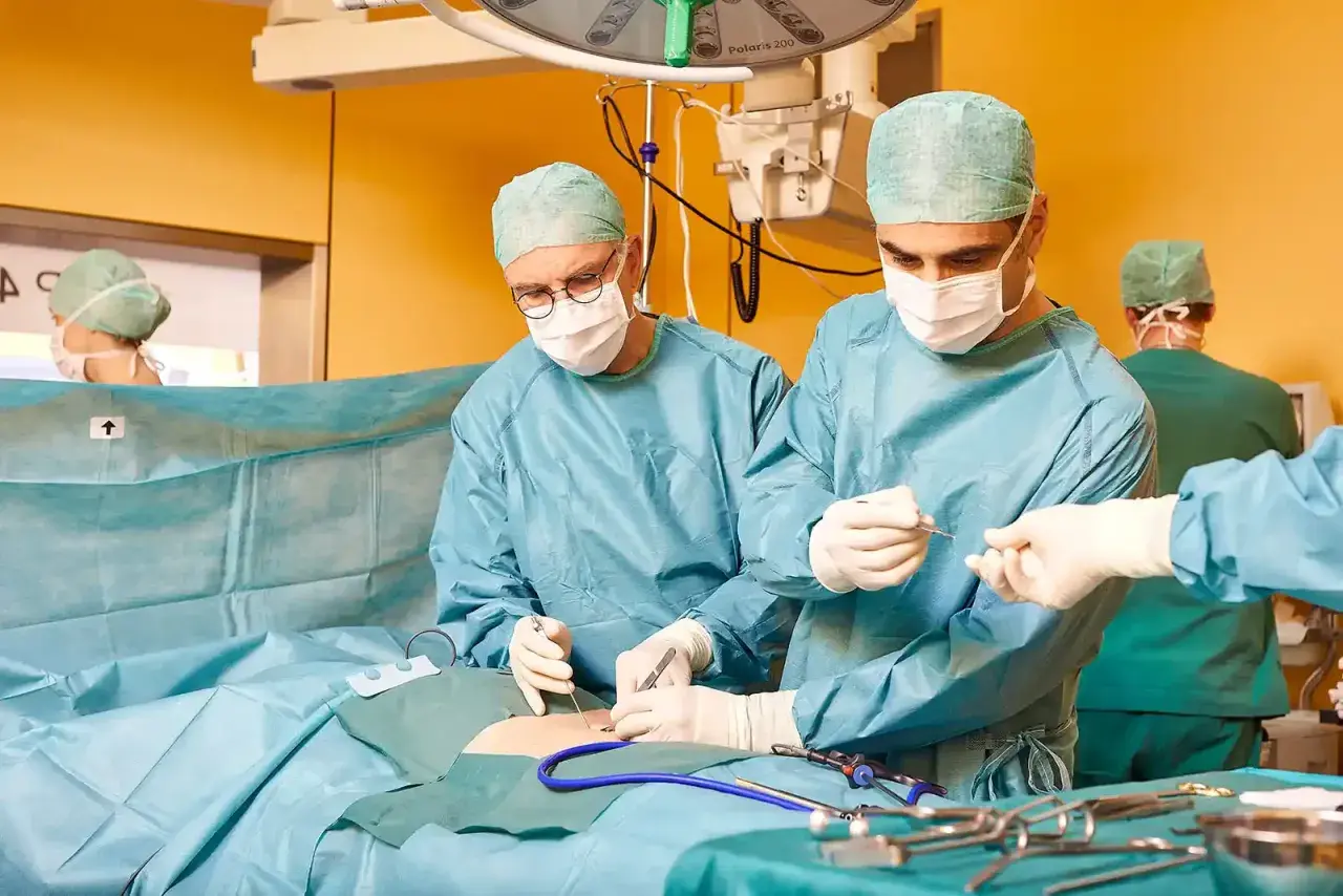 Chirurgen führen eine Hernien-OP mit Netz durch. Ein Team arbeitet konzentriert, um Komplikationen zu vermeiden.