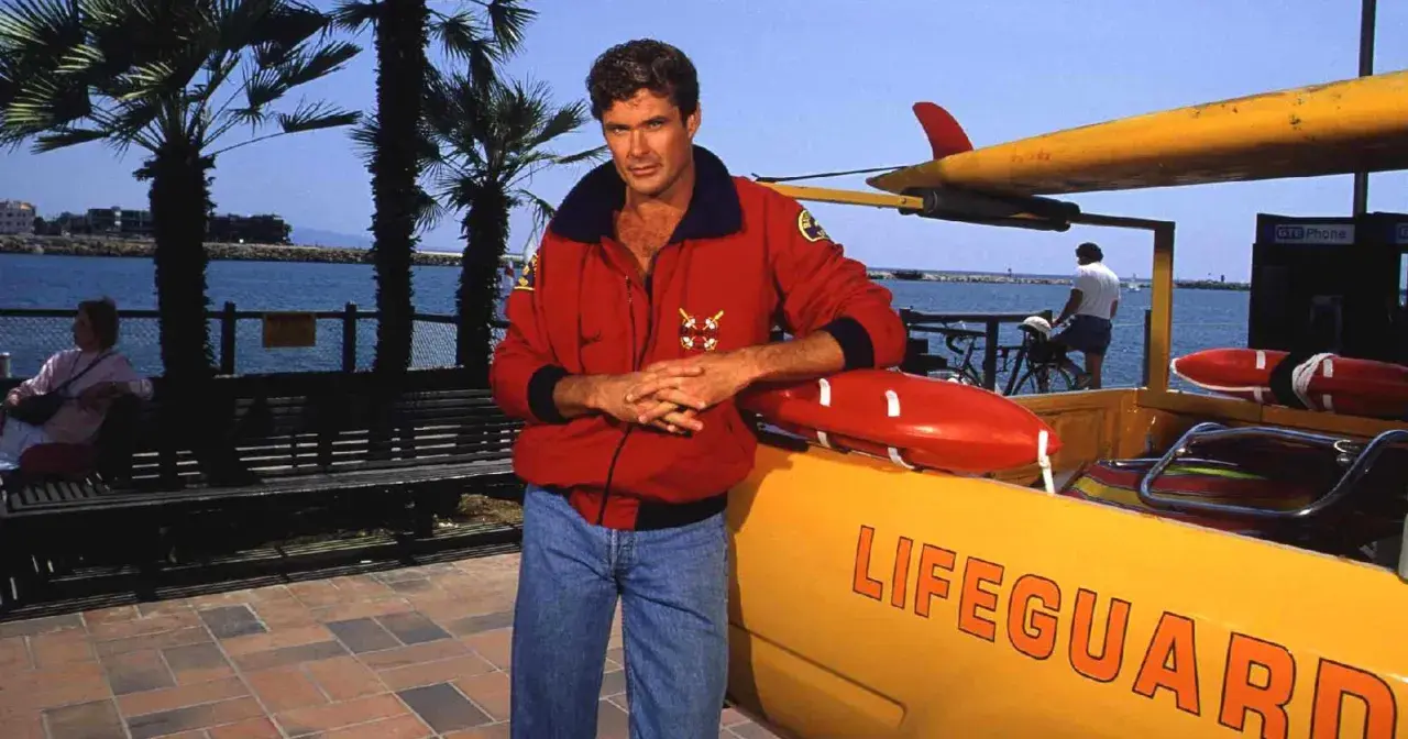 David Hasselhoff, ikona serialu Baywatch Słoneczny Patrol, pozuje przy łodzi ratowniczej.