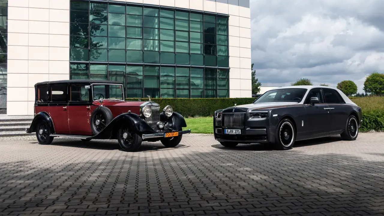 Dwa Rolls-Royce'y Phantom: zabytkowy czerwono-czarny i nowoczesny grafitowo-biały, stojące przed budynkiem.