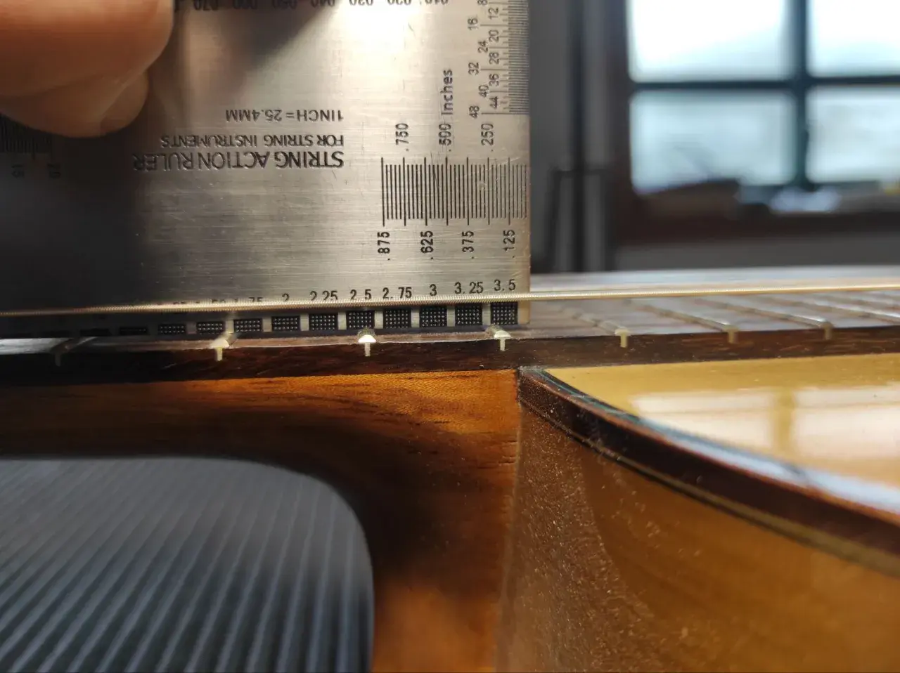 Ajustando la altura de las cuerdas de una guitarra flamenca con una regla de acción.