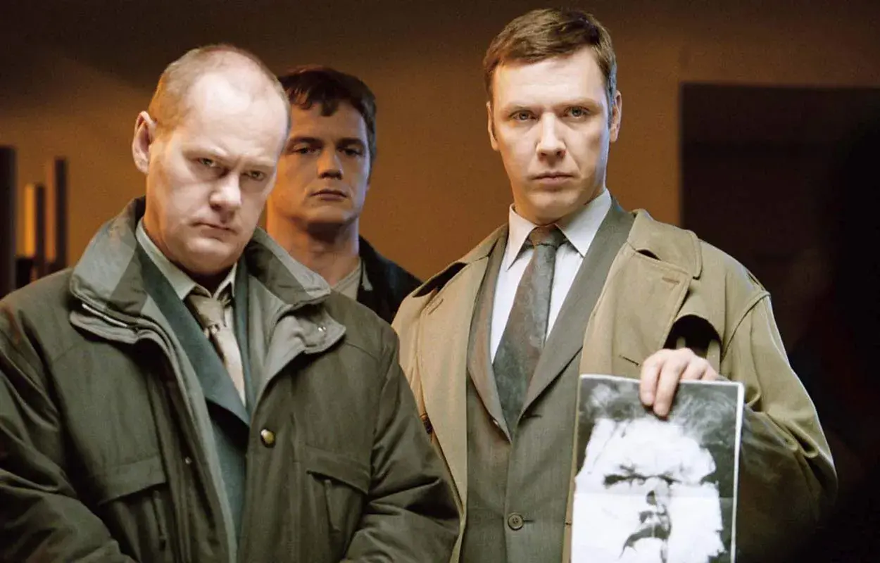 Mikael Persbrandt i en scen från filmer och tv-program. Han håller upp ett fotografi av en man.