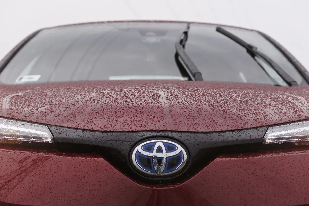 Czerwona Toyota z kroplami deszczu na masce i logo. Czy toyota ma ocynkowane blachy? Ta z pewnością jest dobrze zabezpieczona.