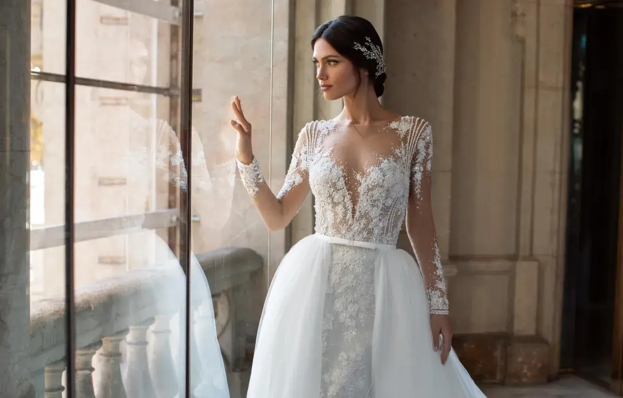 Elegancka panna młoda w sukni z koronki i tiulu, z ozdobną biżuterią we włosach. Inspiracja dla fryzur na ślub.