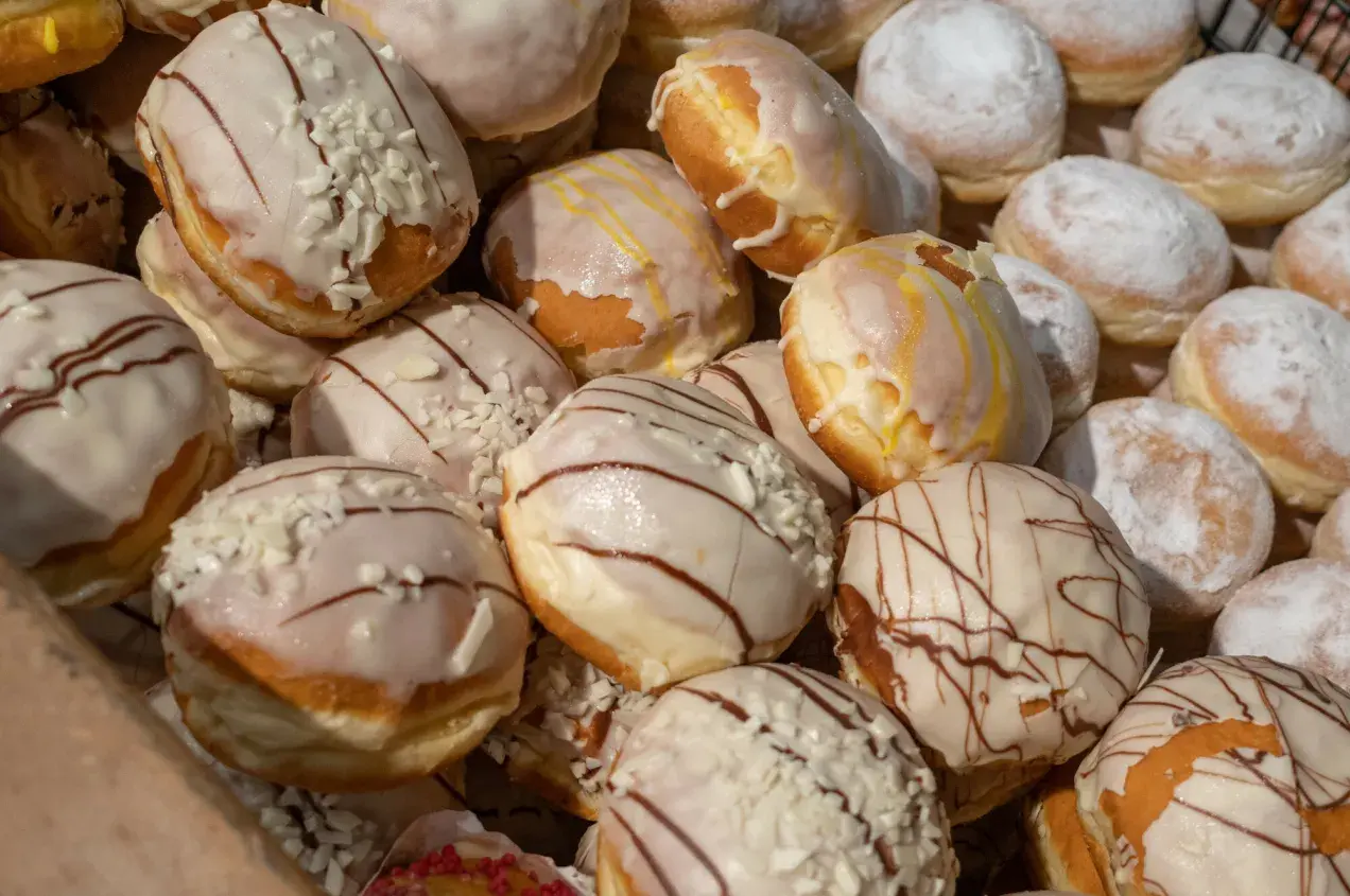 Pączki z lukrem i posypką, niektóre z polewą czekoladową. Czy paczki można mrozic? Tak, można je zamrozić, by cieszyć się nimi dłużej.