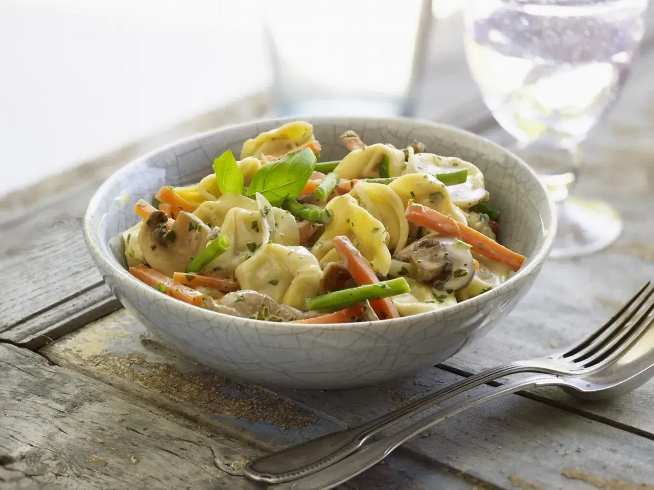 Tortellini con champiñones, zanahoria y espárragos en una cremosa salsa para pastel de verduras.