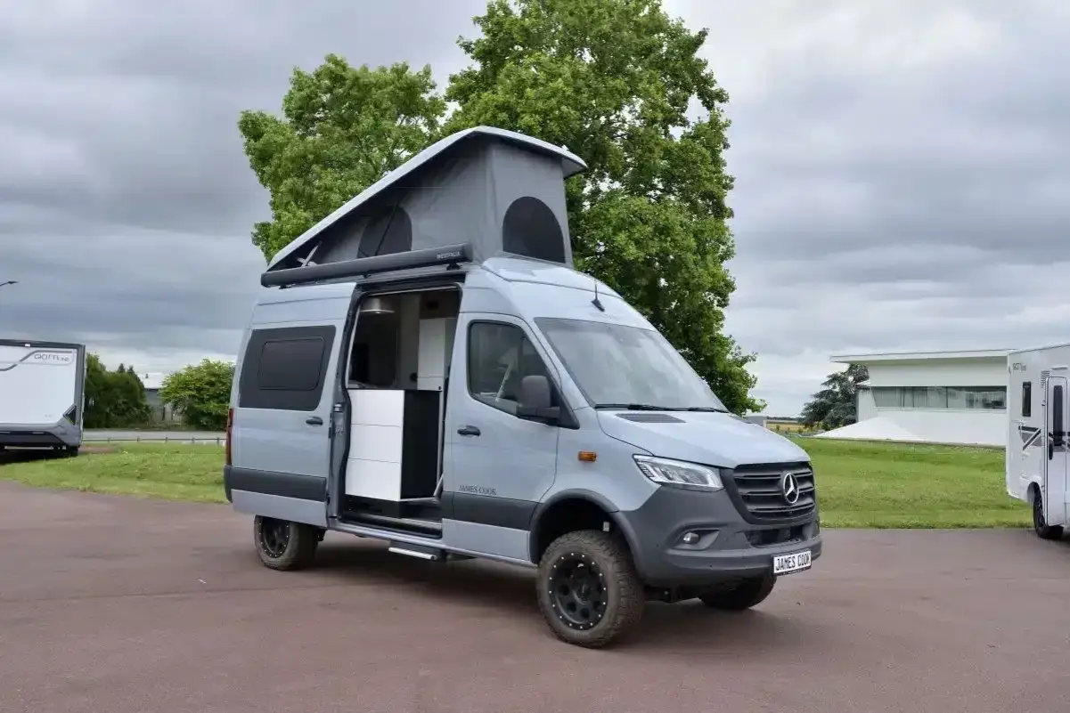 Le plus grand fourgon aménagé, un Mercedes gris avec toit relevable, prêt pour l'aventure.