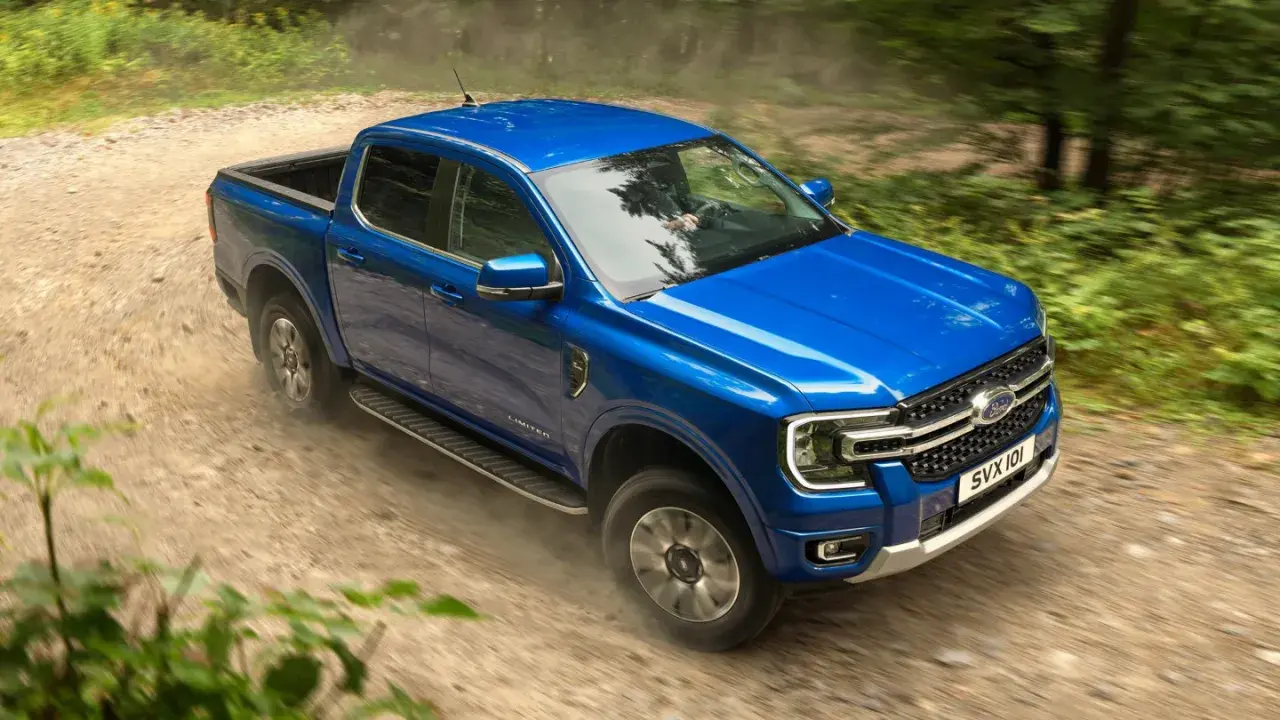 Blå Ford Ranger laddhybrid kör på en grusväg genom en skog.