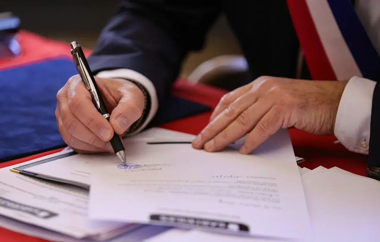 Mano firmando un documento oficial. El **valor pericial** de este acto es la validación de un acuerdo o testimonio.