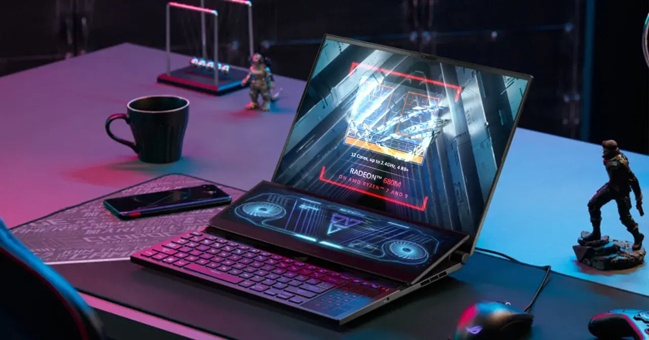 Laptop z ekranem głównym wyświetlającym specyfikację AMD Radeon 680M na procesorze Ryzen 7/9. Obok klawiatura i dodatkowy ekran.
