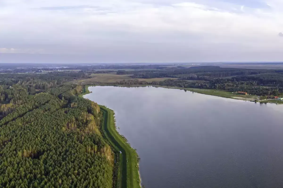Rozległy zalew Biszcza otoczony lasem i zielonymi łąkami. Spokojna tafla wody odbija niebo.