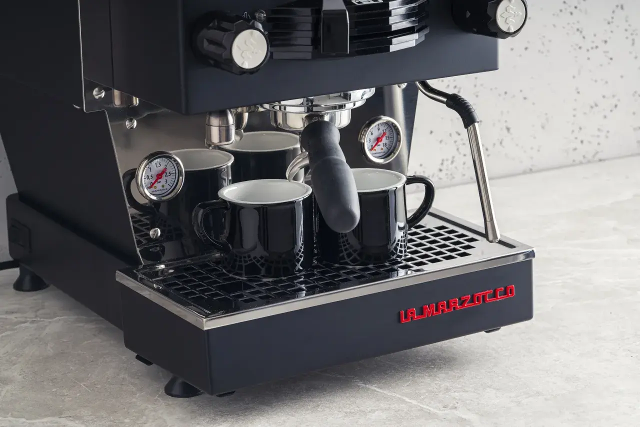 Profesjonalny ekspres do kawy La Marzocco z dwoma czarnymi filiżankami. Dowiedz się, jak odpowietrzyć ekspres Delonghi, by cieszyć się idealnym espresso.