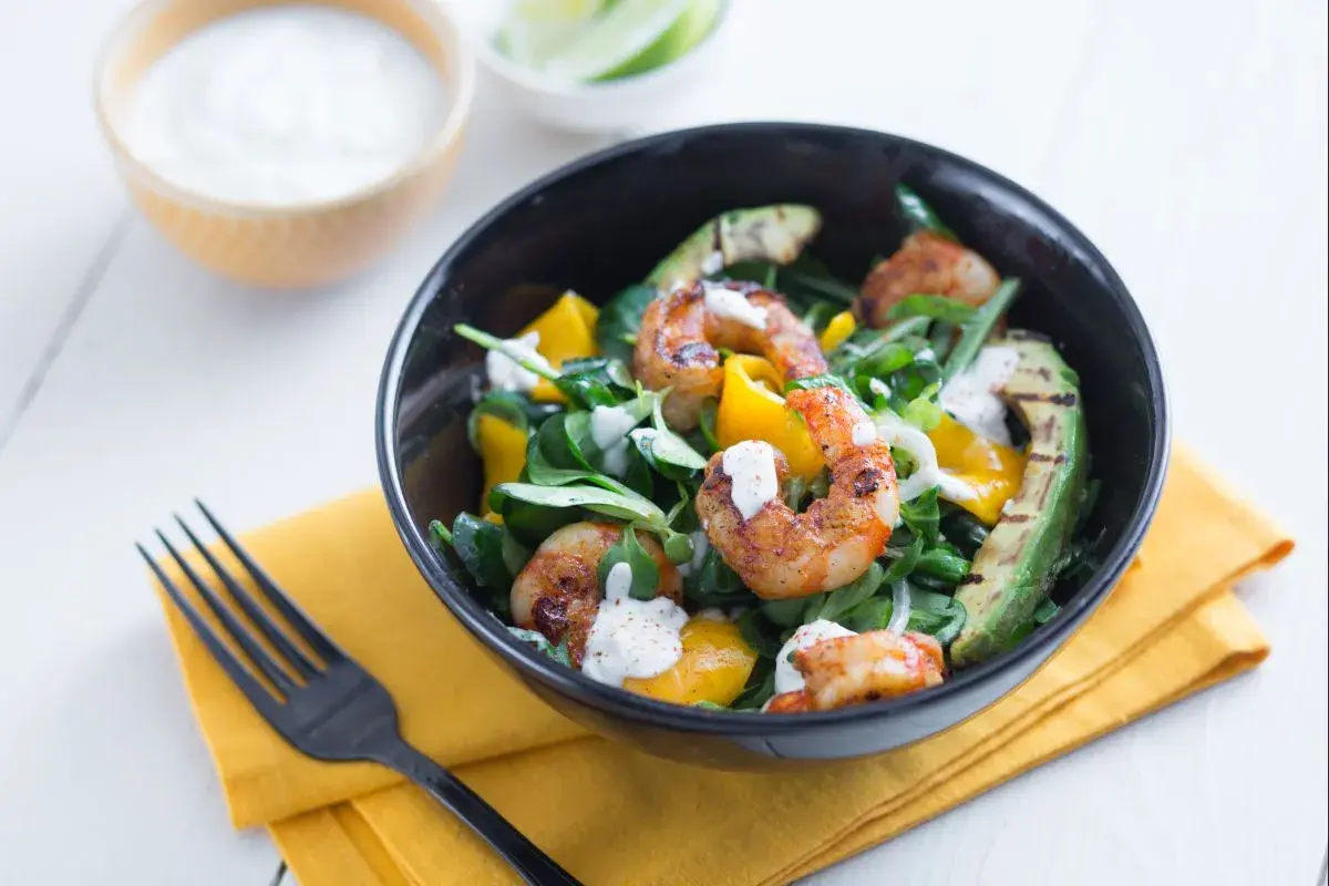 Garnelensalat mit Avocado und Mango, beträufelt mit einer cremigen Sauce.