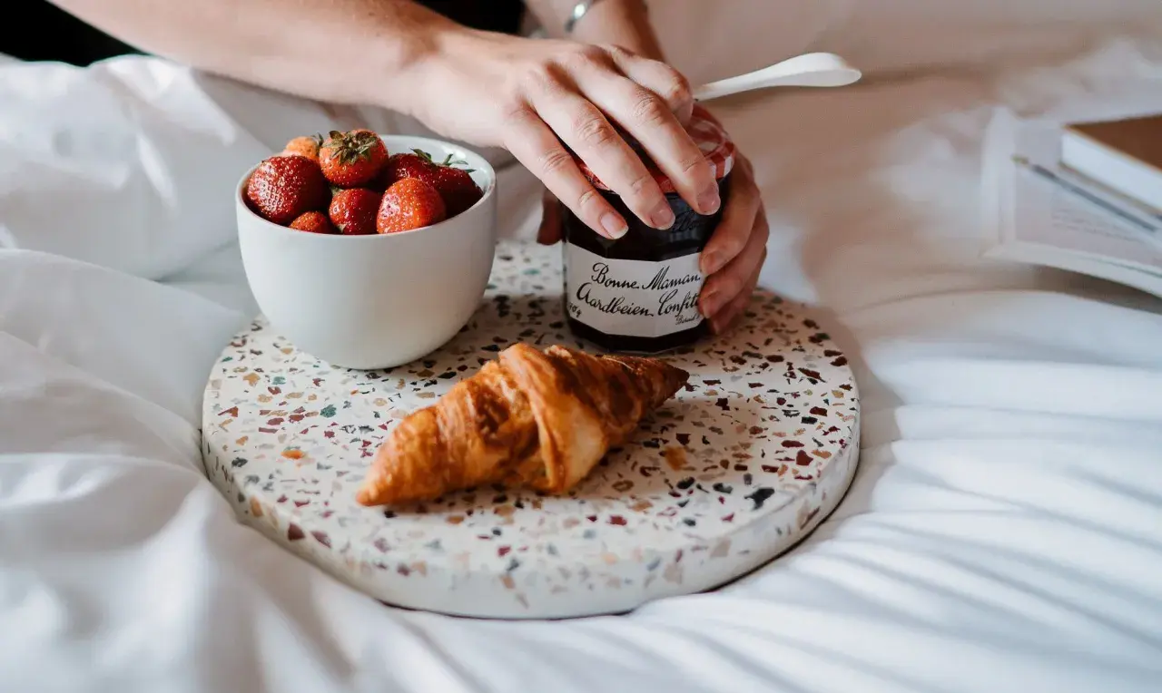 Een croissant, aardbeien en confituur op een dienblad. Perfect om te genieten van eten uit verveling op een luie ochtend.